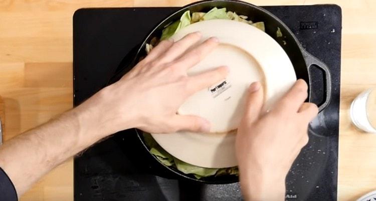 Nous couvrons le chaudron avec des feuilles de chou entières, ainsi qu’une assiette sur le dessus.