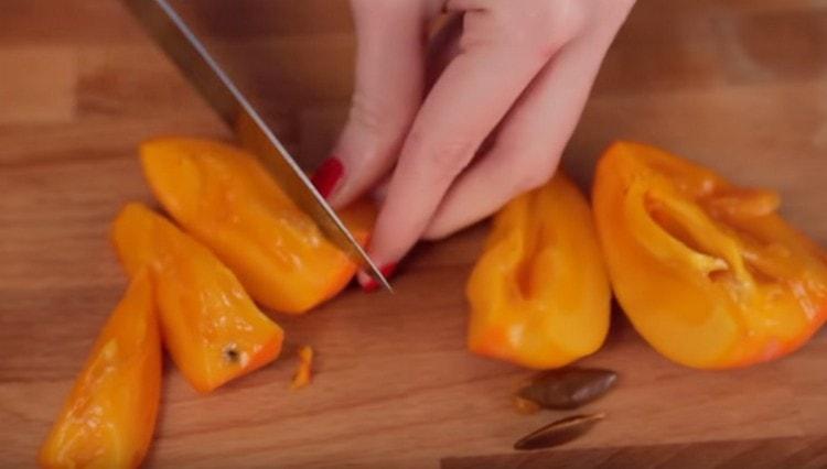 Coji persimoni de pe piele și semințe, tăiate în bucăți.