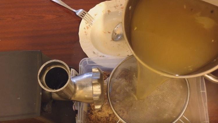 Așezăm carnea pe fundul tăvii și turnăm bulionul într-o sită.