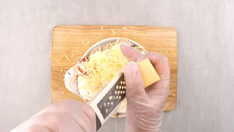 La receta de salmón chum bajo una capa de verduras con crema agria con una corteza de queso dorado
