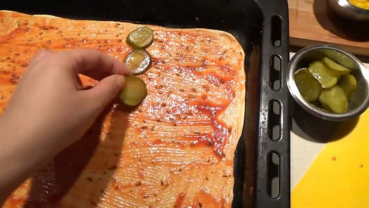 Para hacer los ingredientes de la pizza, ponga los pepinos sobre la masa.