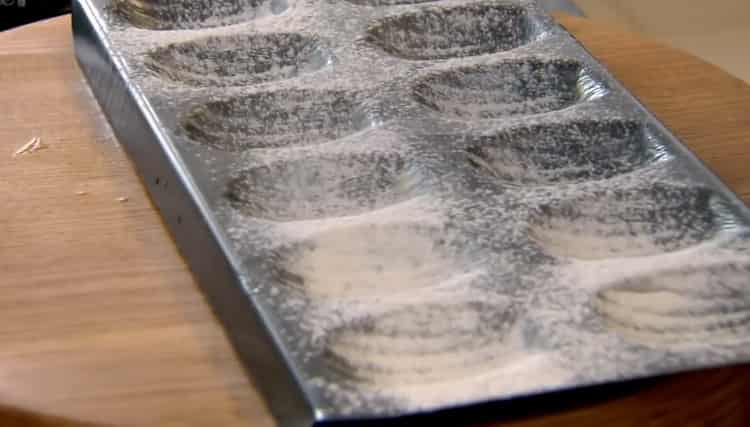 Para hacer galletas de Madeleine, espolvoree la harina con un molde.