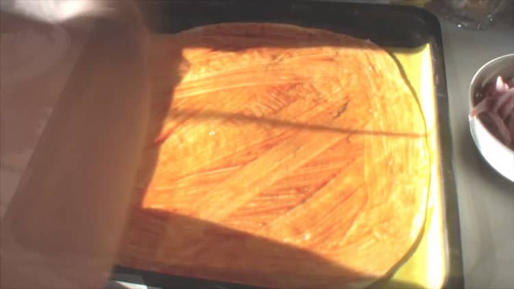 Puneți ketchup-ul pe aluat pentru a face pizza asortată