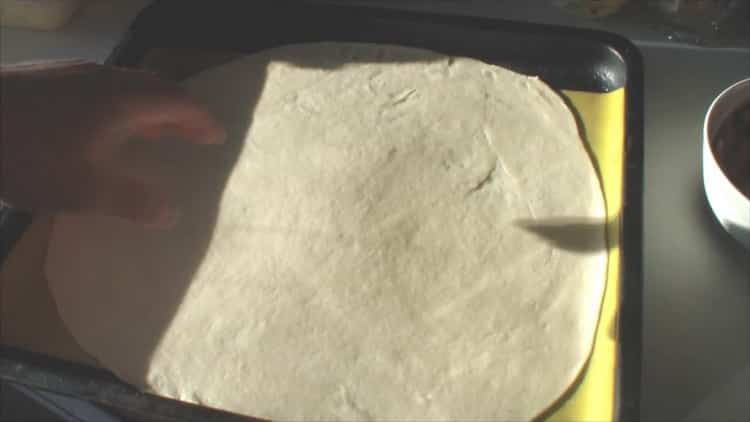 Rulează aluatul pentru a face pizza asortată