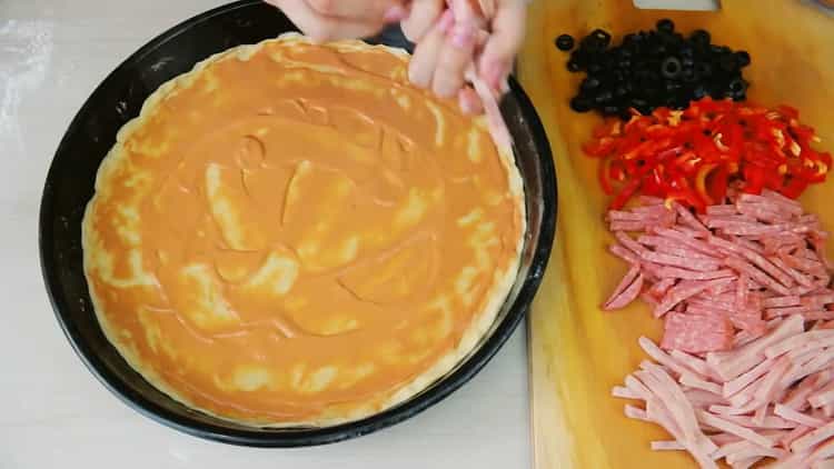 Pentru a face pizza fără drojdie, ungeți aluatul cu sos