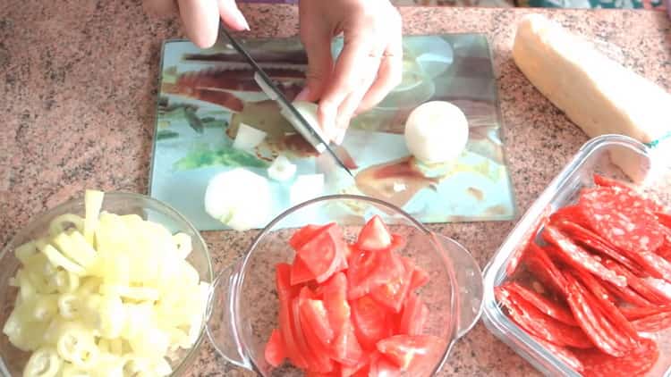 За да направите пица с бутер тесто във фурната, нарежете лука