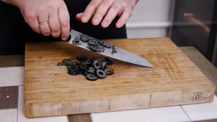 Pentru a face o plăcintă cu pizza, toacă măslinele