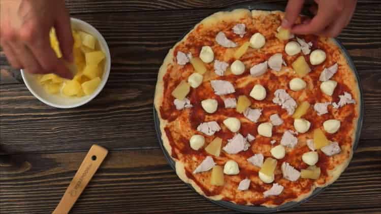 Pentru a pregăti pizza cu pui și ananas, așezați umplutura pe bază
