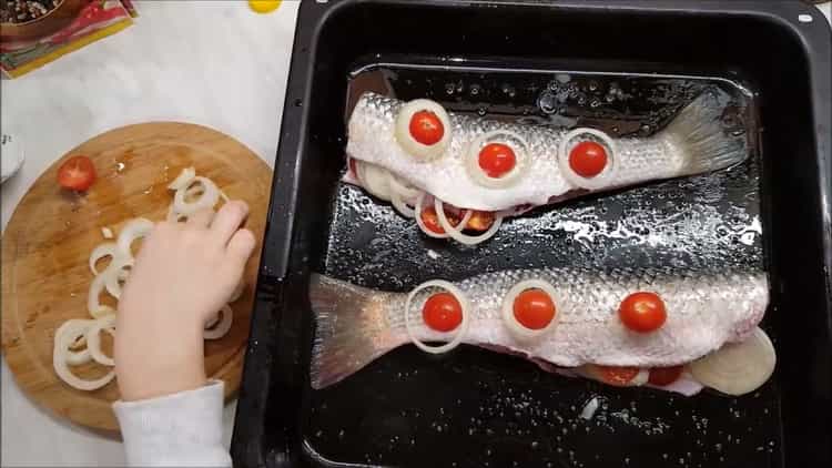 Para cocinar un rodamiento en el horno, ponga los tomates sobre el pescado.