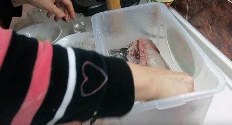 Nous répandons le premier morceau de poisson et le graissons avec le mélange préparé pour le salage.