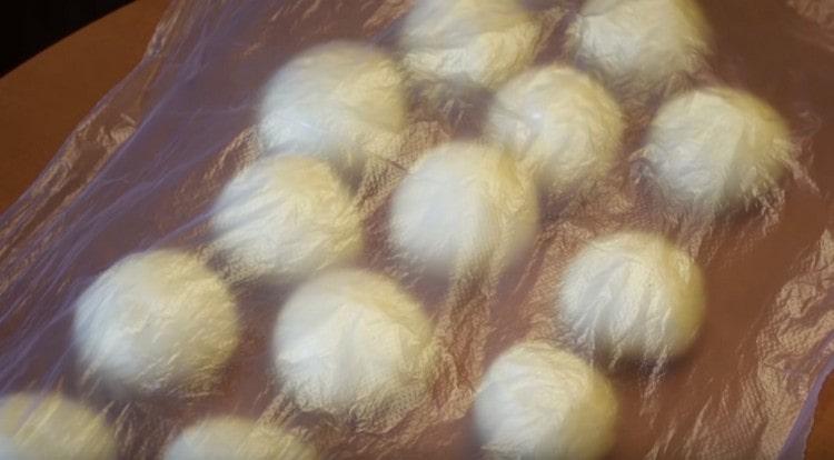 Покриваме топките от тестото със слепващ филм и ги оставяме да втасат.