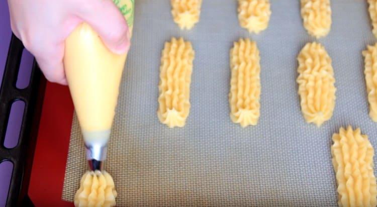 Med en konditorpåse placerar vi eclairs på en bakplåt.