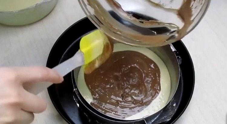 En una fuente de horno engrasada, vierta alternativamente la masa blanca y de chocolate.