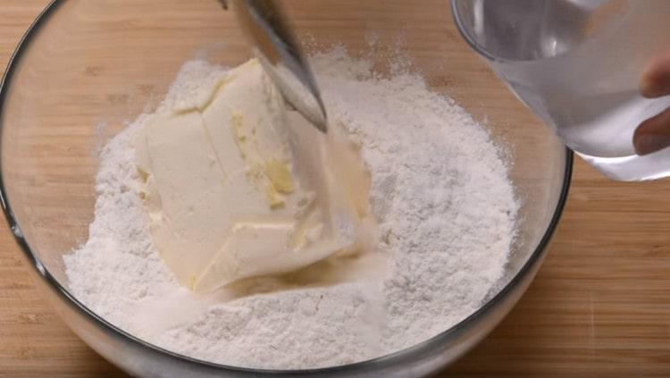 Adăugați unt rece și apă cu gheață în făina cernută.