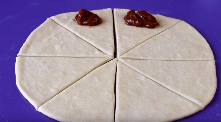 В основата на всеки триъгълник изложи лъжица варено кондензирано мляко.