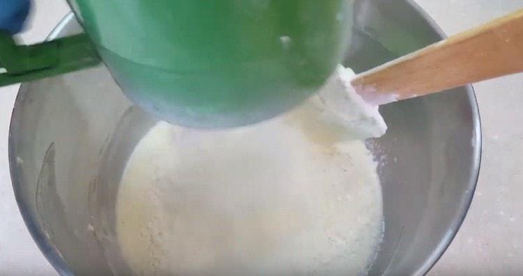 Pag-ayos ng harina at masahin ang masa ng spatula.