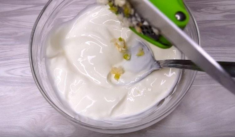 Pentru a face sosul, amestecați smântâna cu usturoiul tocat.