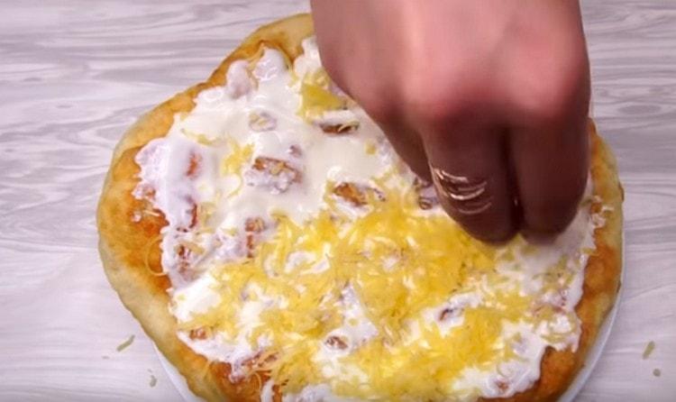 Se unge gogosele gata preparate pe apă cu sos și se presară brânză rasă.