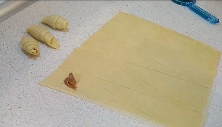 En el lado ancho del triángulo de masa esparcimos el relleno de leche condensada hervida.