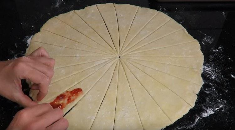 Pentru fiecare triunghi de aluat întindem puțin gem.