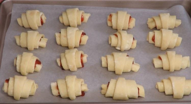 Împărțim baghetele de la brânza de casă pentru foaia de copt acoperită cu pergament și o trimitem la cuptor.