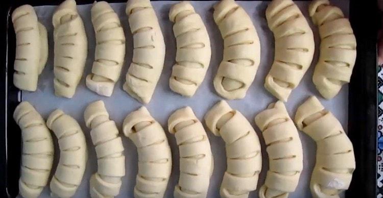 Bagelele formate puse pe o foaie de copt acoperită cu hârtie de copt.