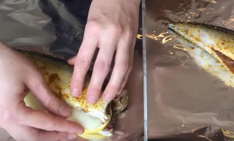 В корема на рибата слагаме няколко резенчета лук и лимон.