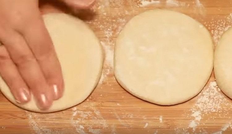 Después de rociar la mesa con harina y almidón, esparcimos tres pasteles planos sobre ella.