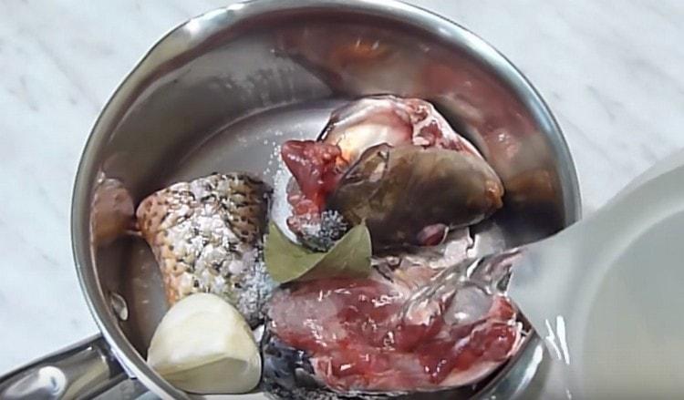 Ponemos la cabeza y la cola de la carpa en la sartén, agregamos la cebolla, la hoja de laurel y la llenamos de agua.