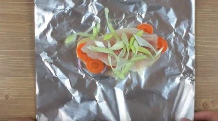 Den Fisch auf das Gemüse legen, mit Lauch bestreuen und die Sauce einschenken.