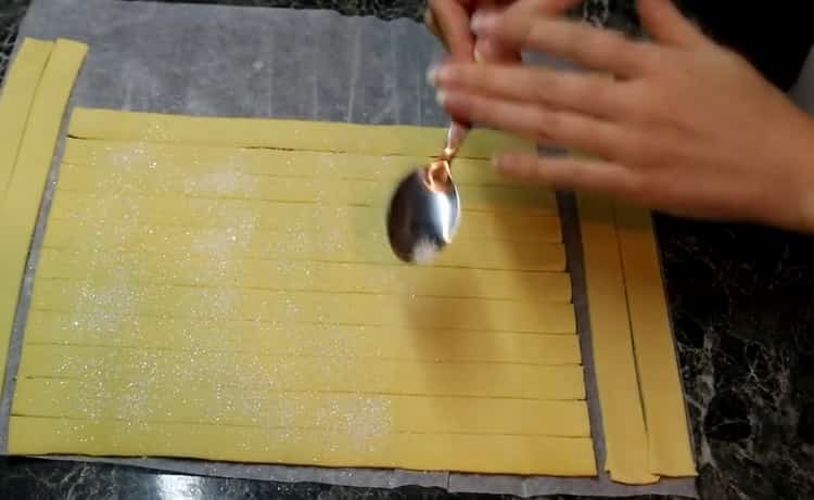 За да направите рози от бутер тесто, поръсете тестото със захар