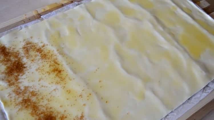 Untuk membuat telinga kue puff, letakkan gula pada doh