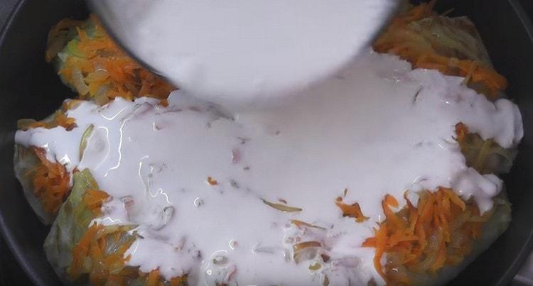 Vi overfører udstoppet kål til panden, fordeler grøntsager fra gryden ovenfra, hæld alt med creme fraiche.