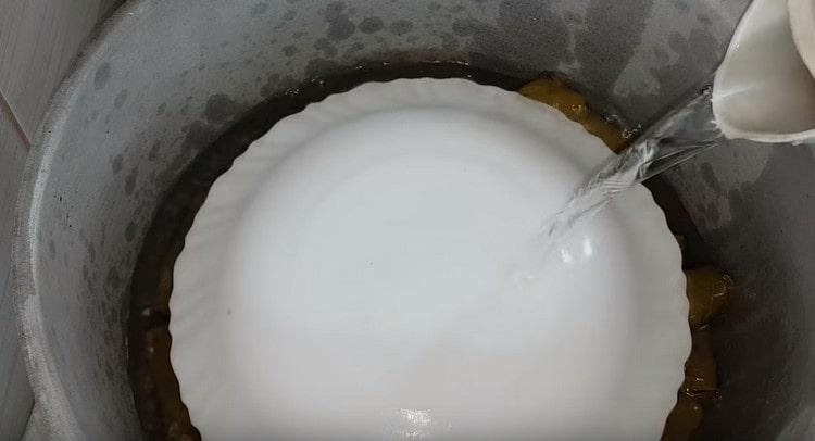 Rolky zelí zakryjte deskou a naplňte vodou.