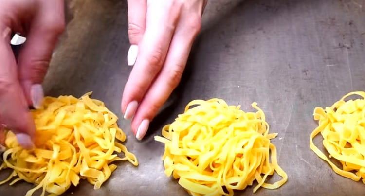 Sur une plaque à pâtisserie recouverte de papier sulfurisé, étalez des portions de nouilles.