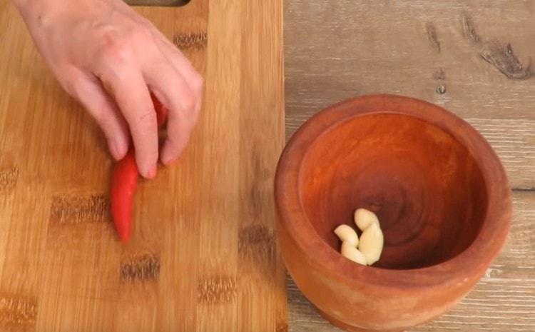 Puneți usturoiul decojit în mortar.