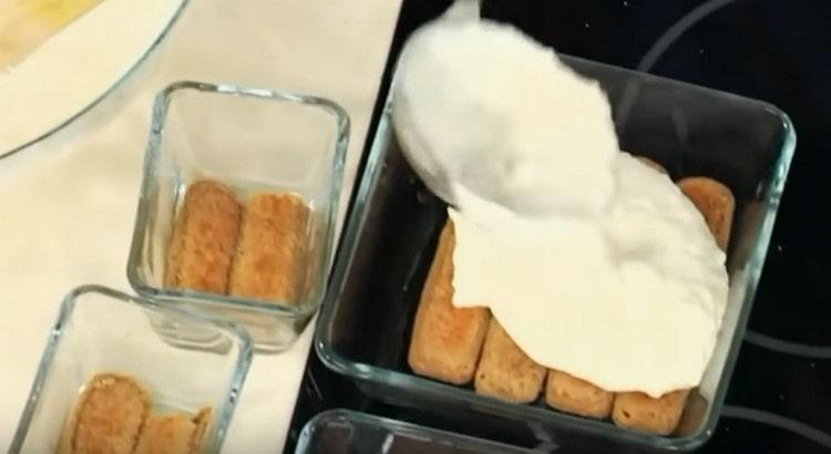 Tauchen Sie die Savoyardi-Kekse in Kaffee mit Cognac, geben Sie sie in Dosen und bedecken Sie sie mit Sahne.