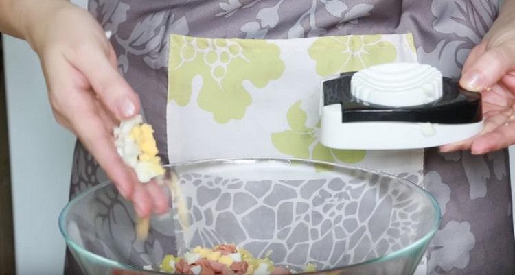 С помощта на филийката за яйца нарязваме яйцата.