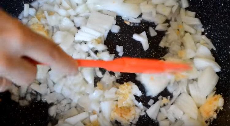 Prăjiți ceapa cu usturoi într-o tigaie.