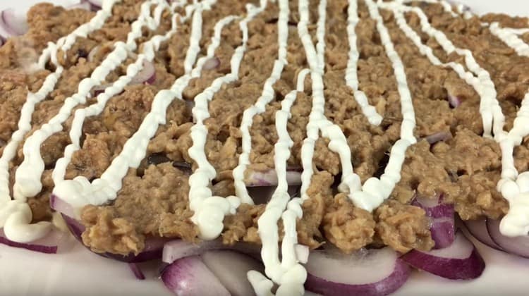 Machen Sie ein Mayonnaise-Netz auf einer Thunfischschicht.