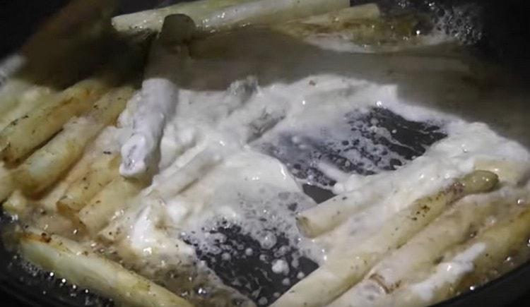 Adăugați smântână în tigaie în sparanghel.