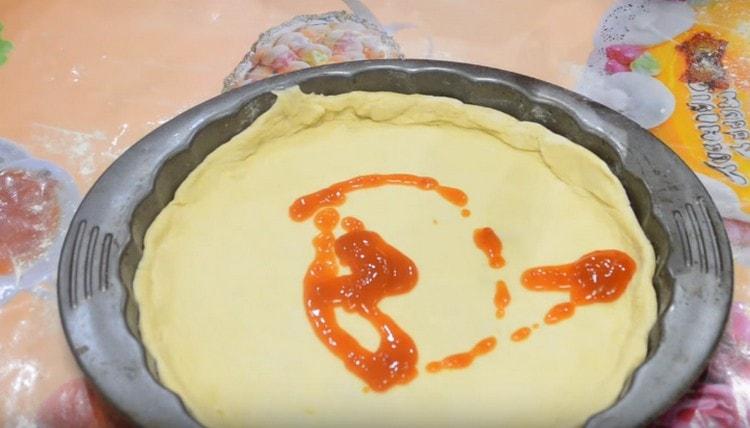 Смажете основата за пица с доматено пюре.