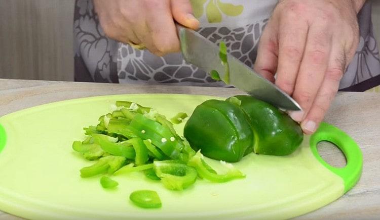 Mientras la carne y la cebolla están fritas, pique el pimiento en tiras.