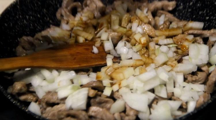 Добавете лука и соевия сос към месото в тигана.