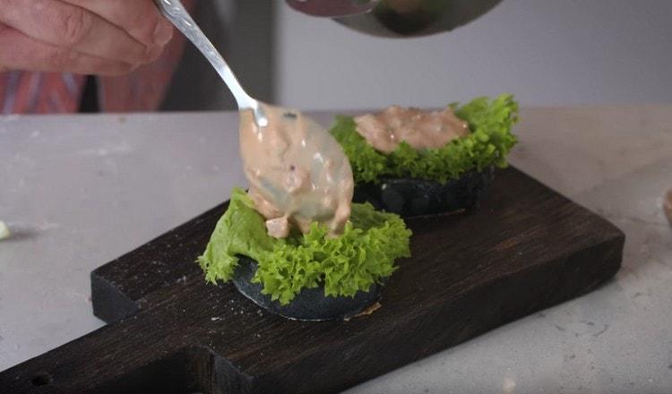 Pe o chiflă, puneți o lingură de sos, o foaie de salată și apoi din nou o lingură de sos.