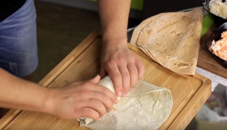 Turning the edges, we turn the pita roll.