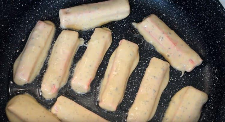 Krabbenstangen in Teig tauchen und in einer Pfanne verteilen.