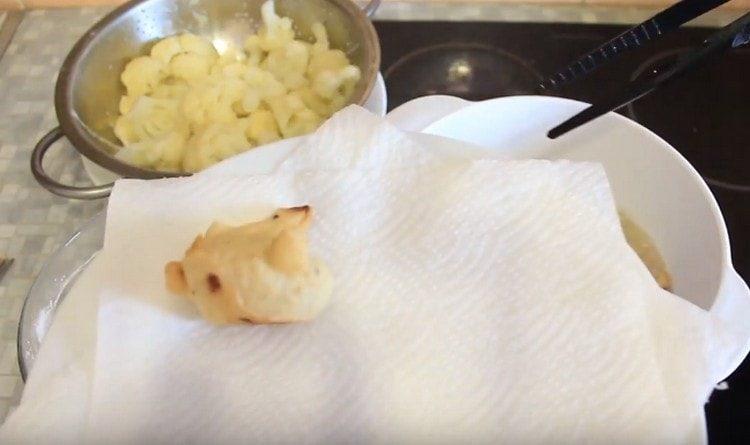 Прехвърляме пържените съцветия на хартиени кърпи.