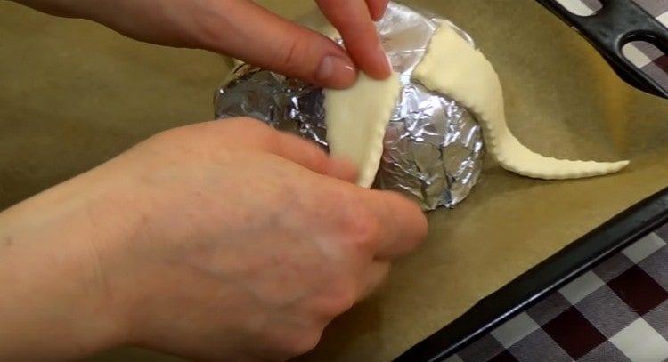 À partir des morceaux de pâte, nous formons les tentacules d'une pieuvre sur une tasse.