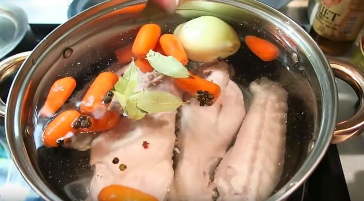 după fierbere, schimbați apa, adăugați morcovul, ceapa, frunza de dafin, boabele de ardei în tigaie.